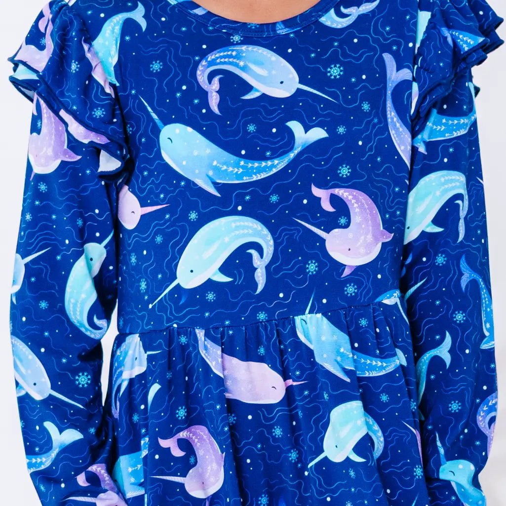 Close up of the front of a long sleeve twirl dress with flutter ruffles at the shoulders in a royal blue print of blue and lavender narwhals.